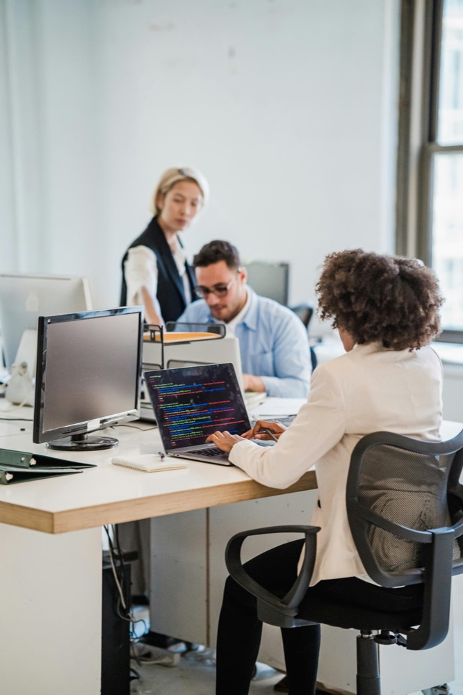 Colleagues collaborating at a shared desk in a bright office.